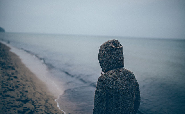 loneliness Generation Z woman walking alone beach