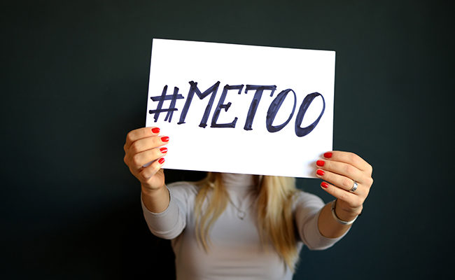 woman holding #MeToo sign church Me Too movement one year anniversary