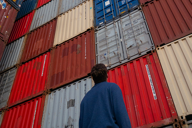 Man looking up at stack of shipping containers - pastors care
