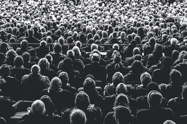 Grayscale photo of people sitting on chairs in crowd - making disciples, not growing a crowd