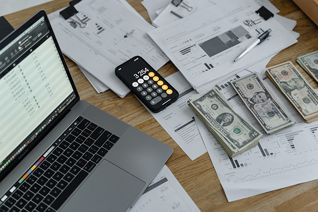 budgeting papers, cash, calculator, and laptop on table - church budgeting