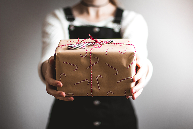 person showing brown paper package tied with string - outreach this Christmas