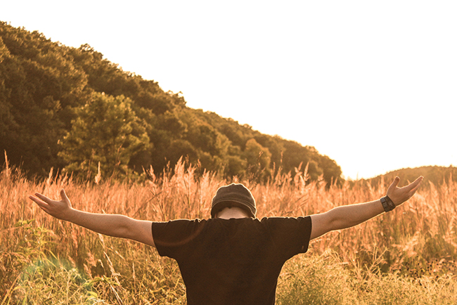 Man on knees facing field with arms open wide - church planters