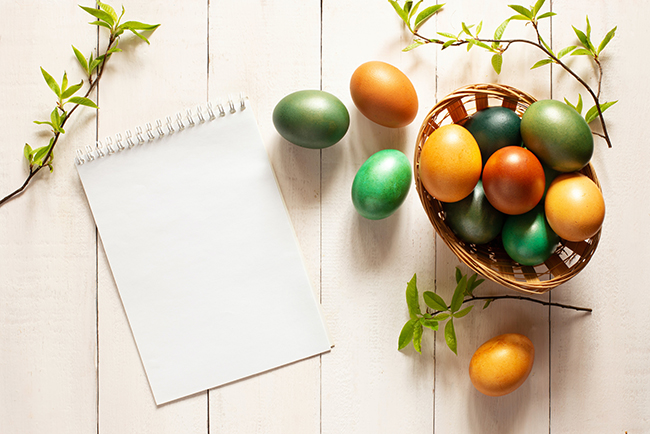 Easter eggs in basket next to blank notebook - preparation
