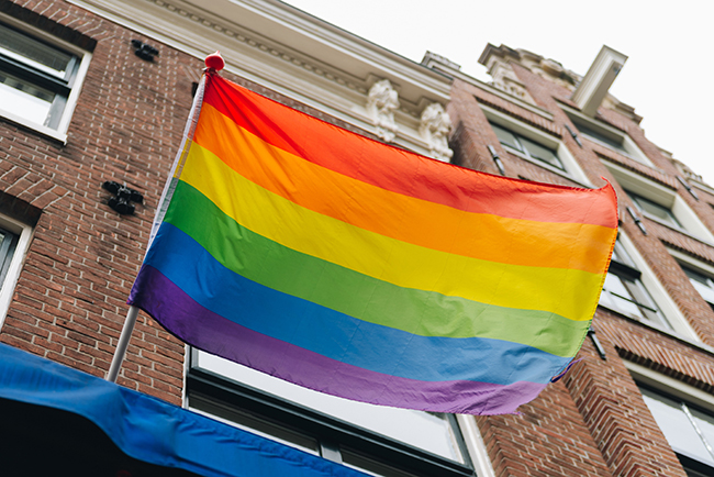 LGBTQ+ flag flying on brick building