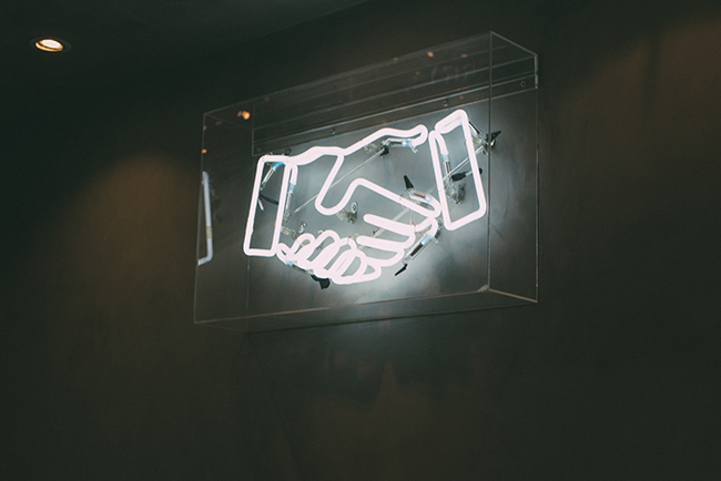Neon sign of hands shaking - mission partner