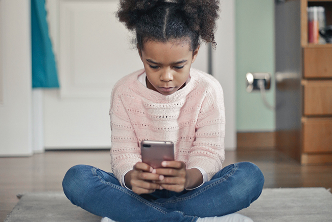 girl sitting on floor holding phone - social media and parenting