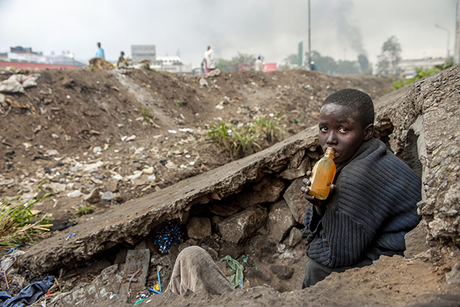 A street boy in Nairobi, Kenya, sniffs glue to ward off hunger pains - global hunger