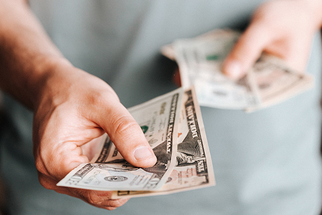 man's hand holding out cash - prosperity gospel