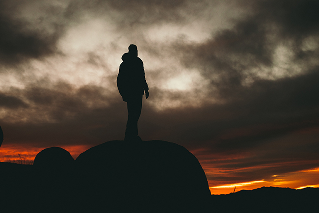 Man standing on rock at sunset - What does the Bible say about fear?