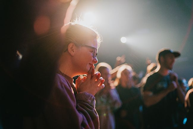 Selective focus photo of woman praying in worship service - new normal for churches