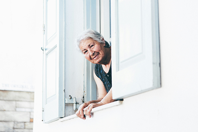 Older woman peering out of window - blessing of growing old