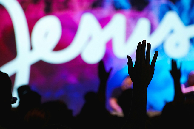 Silhouette of person's hand raised in worship - Easter attendance