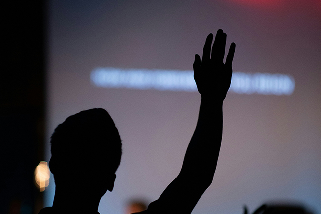 Silhouette of man raising hand in worship - bilingual worship